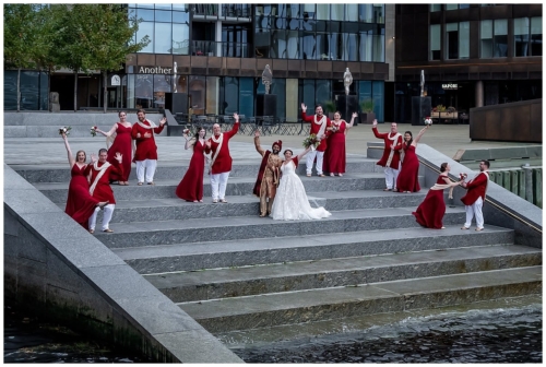 A bengali groom and his western wife pose with their wedding party for fun photos on the steps edge of the Halifax Harbour.