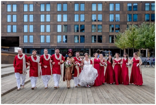 The wedding party link arms as the walk along the Halifax harbourfront together for wedding photos.