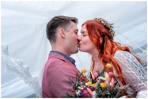 The bride and groom kiss under the bridal veil during their wedding photos in Bear Cove NS.